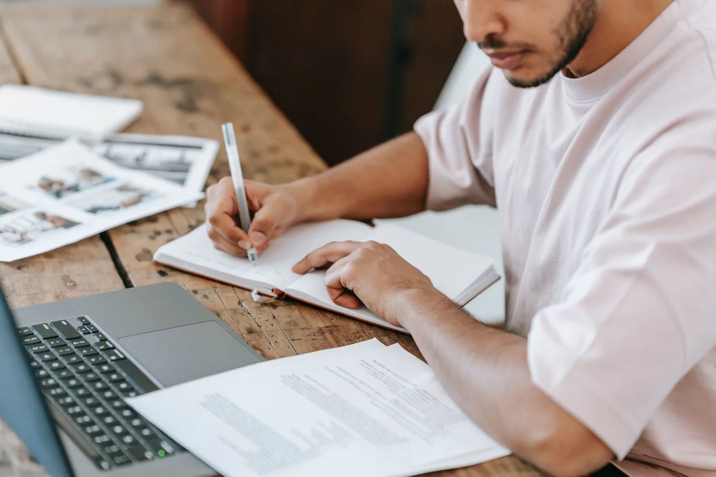 A student taking notes beside a laptop